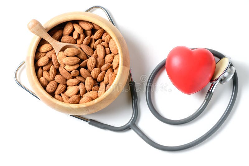 Almonds in a wood cup with stethoscope and a red heart isolated on white. Almonds contain high-density lipoprotein HDL cholesterol and help prevent heart stock image