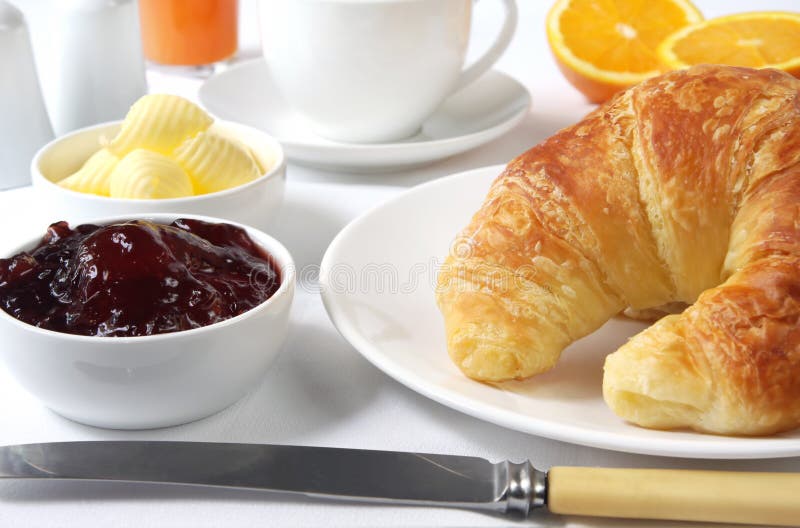 Continental breakfast with croissants, strawberry jam and butter, coffee, and fresh orange juice. A sunlit morning feast. Continental breakfast with croissants, strawberry jam and butter, coffee, and fresh orange juice. A sunlit morning feast.