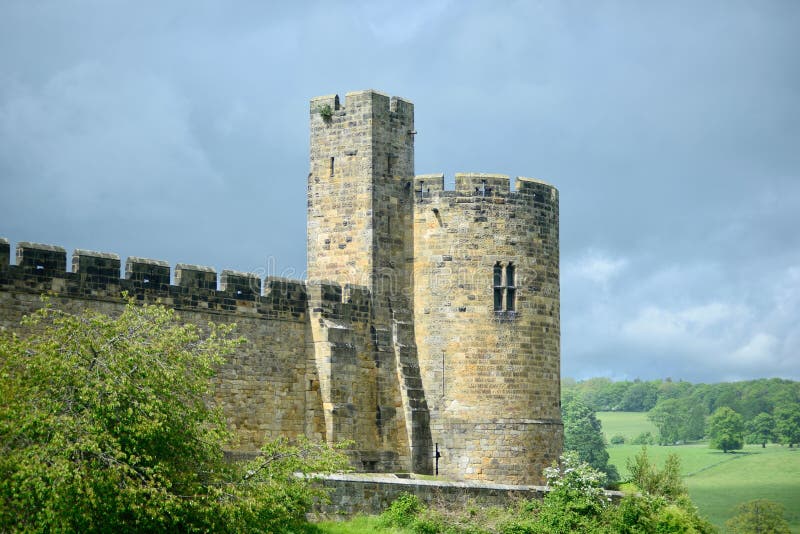Alnwick Cast Surrounded by Lush Green Trees and a Cloudy Sky in the