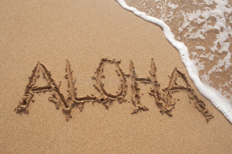 Close up of the Hawaiian word Aloha written in the sand on the beach in Hawaii with a wave breaking in the top right hand corner. Close up of the Hawaiian word Aloha written in the sand on the beach in Hawaii with a wave breaking in the top right hand corner.
