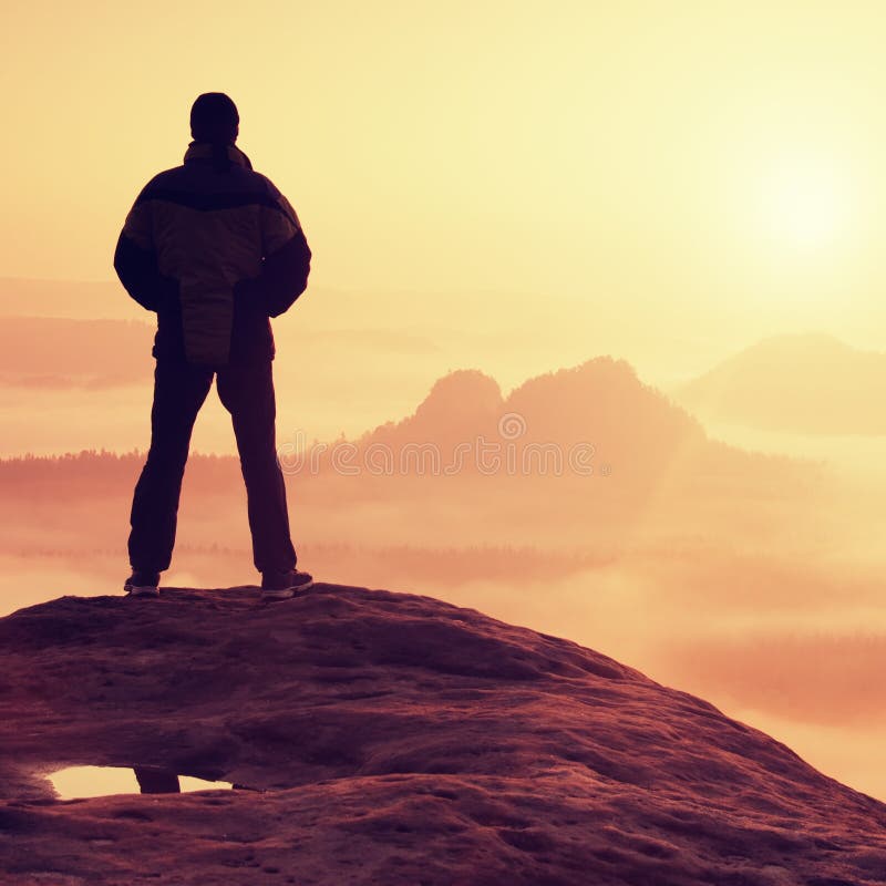 Alone Hiker Standing on Top of a Mountain and Enjoying Sunrise Stock