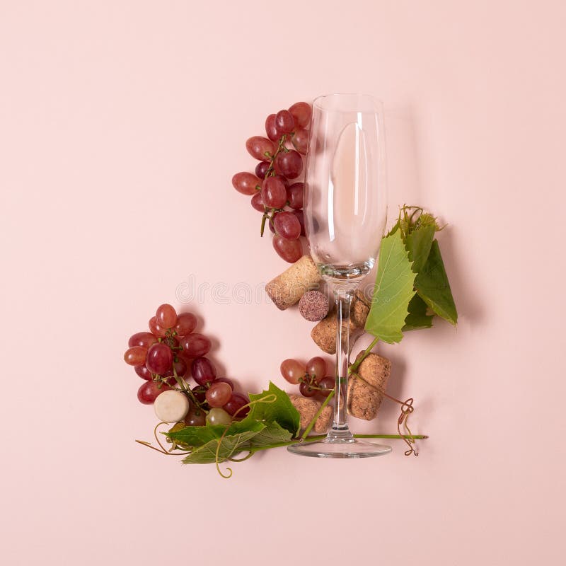 Alphabet Buchstabe J machte von den Weingläsern mit der Rose und Weißwein, Trauben, Blätter und Korken, die auf rosa Hintergrund stockfotos
