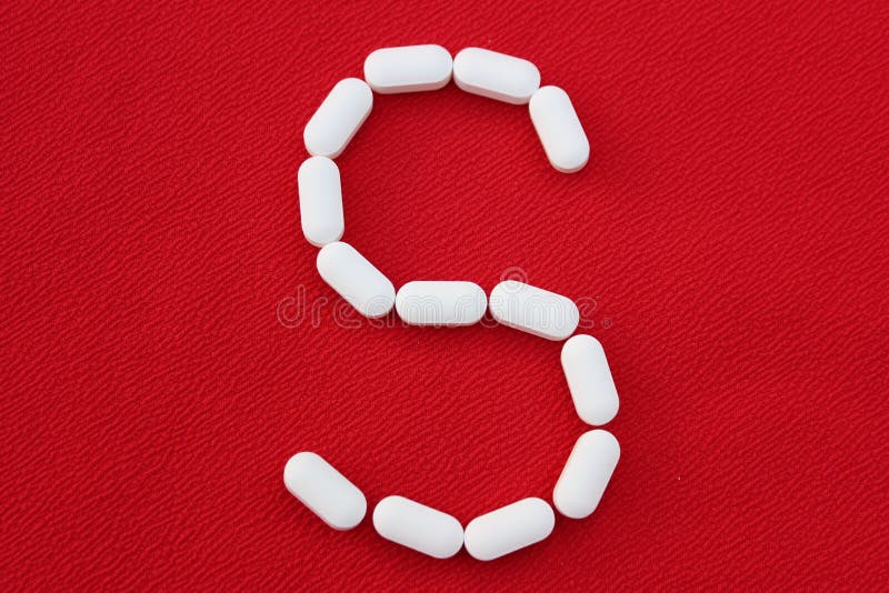 Alphabet made of pills on a red background. Abc from drugs.  Letter S made from pills. Capital letter S of medicines