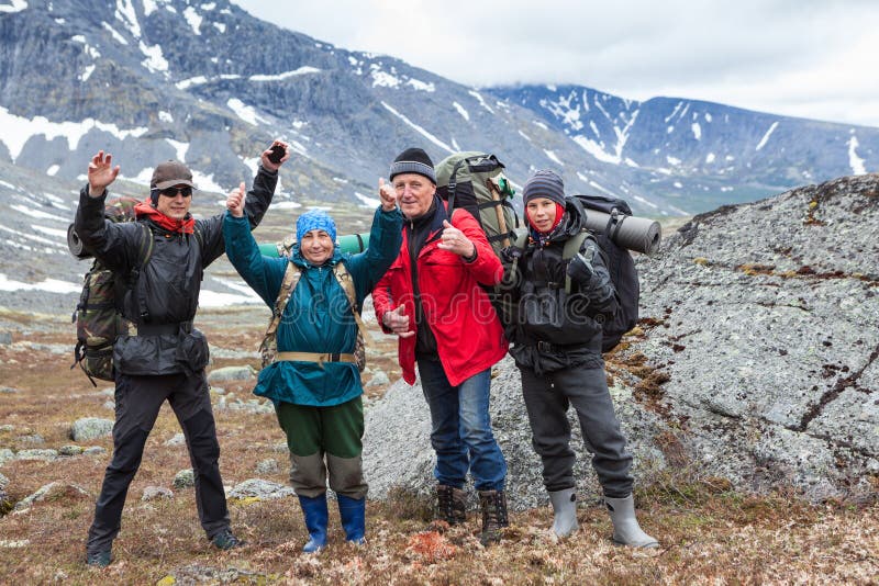 Alpinistes encourageant et saluent les mains vers le haut du groupe de randonneurs caucasiens d'une famille trimardant avec des sa