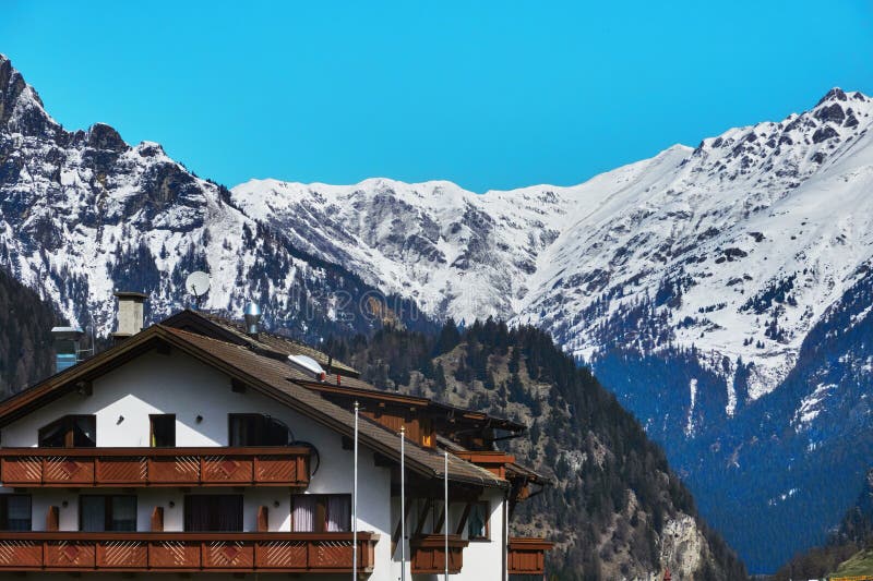 Scenic view of a mountain chalet with snowy peaks in the background in Tyrol in Italy. Scenic view of a mountain chalet with snowy peaks in the background in Tyrol in Italy