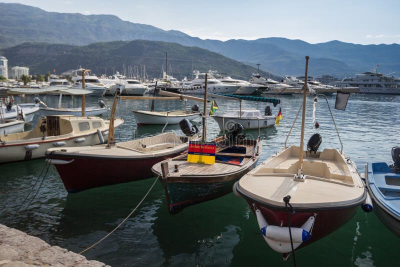 Alte Boote am Pier auf dem Hintergrund von Bergen und von Yachten lizenzfreie stockfotos Alte Boote am Pier auf dem Hintergrund von Bergen und von Yachten lizenzfreie stockfotos