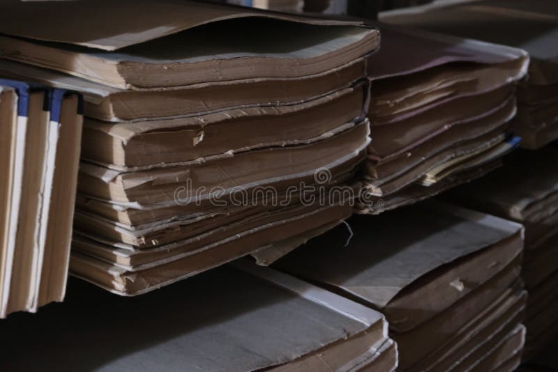 Old books on the bookshelves of the dark archive room of the library. Selective focus. Basement light in the book depository. Copy space. Blurred background. Bundles of documents or filing of newspapers. The concept of historical studies back to school and getting knowledge. Old books on the bookshelves of the dark archive room of the library. Selective focus. Basement light in the book depository. Copy space. Blurred background. Bundles of documents or filing of newspapers. The concept of historical studies back to school and getting knowledge