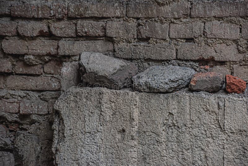Alte, dunkle Ziegelwand mit Steinen stockfotos