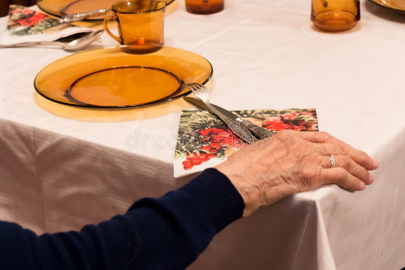 Alte Frau, die Hand auf Tabelle sitzt und hält stockfotografie Alte Frau, die Hand auf Tabelle sitzt und hält stockfotografie