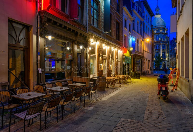 Old cozy narrow street with tables of restaurant in historic city center of Antwerpen Antwerp, Belgium. Night cityscape of Antwerp. Architecture and landmark of Antwerpen. Old cozy narrow street with tables of restaurant in historic city center of Antwerpen Antwerp, Belgium. Night cityscape of Antwerp. Architecture and landmark of Antwerpen