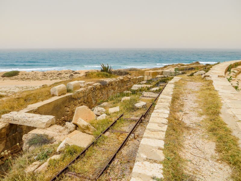 Alte italienische Bahnstrecken unter alten römischen Ruinen auf der Mittelmeerküste von Libyen in Leptis Magna lizenzfreies stockfoto Alte italienische Bahnstrecken unter alten römischen Ruinen auf der Mittelmeerküste von Libyen in Leptis Magna lizenzfreies stockfoto