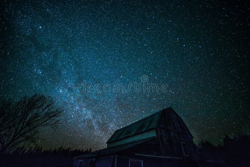 An old ontario barn with gambrel roof on a rural farm is silhouetted in the night sky. The winter Milky way is brilliant. Trees are also silhouetted. An old ontario barn with gambrel roof on a rural farm is silhouetted in the night sky. The winter Milky way is brilliant. Trees are also silhouetted.