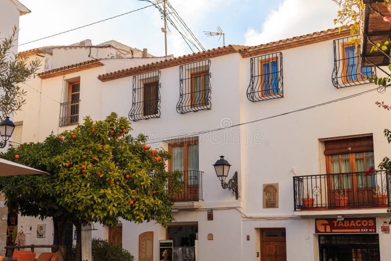 Altea, Spanien - 19. Februar 2019: Ansicht eines weißen Hauses mit einem mit Ziegeln gedeckten Dach und Balkone und eine geschmie stockbilder Altea, Spanien - 19. Februar 2019: Ansicht eines weißen Hauses mit einem mit Ziegeln gedeckten Dach und Balkone und eine geschmie stockbilder