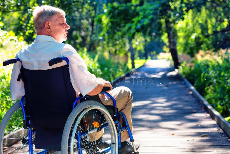 Alter Mann auf Rollstuhl auf dem Weg im Park lizenzfreies stockbild Alter Mann auf Rollstuhl auf dem Weg im Park lizenzfreies stockbild