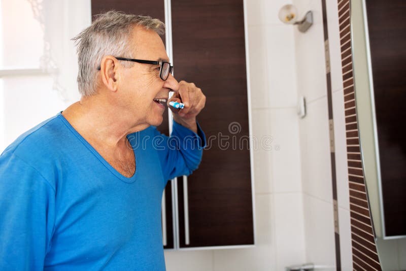 Alter Mann, der Zähne noch in seinen Pyjama putzt lizenzfreie stockfotos