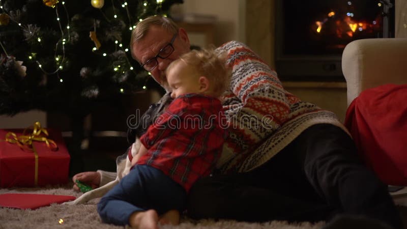Alter Mann und Kind feiern Weihnachtsglückliche Familie. Großvater und Enkel und der Hund haben den Spaß, der auf dem Teppich lieg