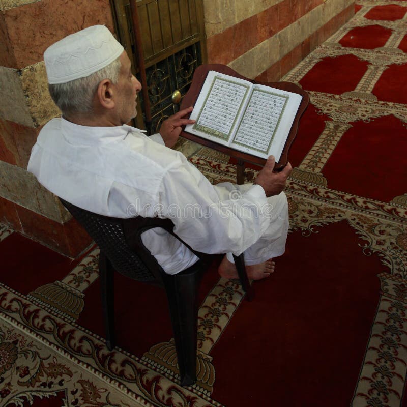 Alter moslemischer Mannlesungsquran in einer Moschee stockfotografie Alter moslemischer Mannlesungsquran in einer Moschee stockfotografie