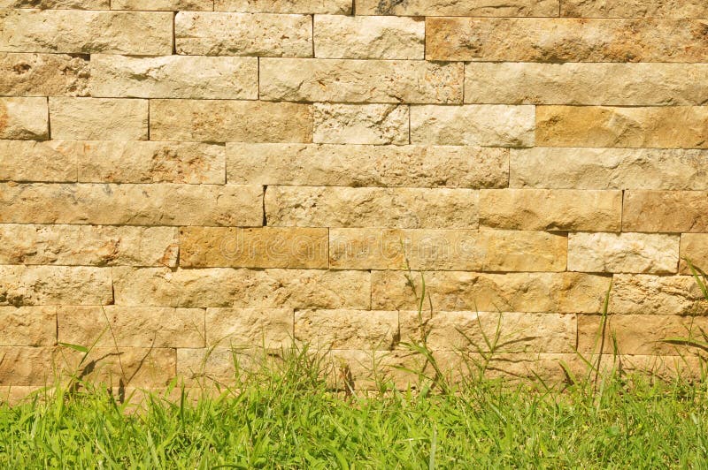 Alter Ziegelsteinsteinwandhintergrund mit Gras lizenzfreies stockfoto Alter Ziegelsteinsteinwandhintergrund mit Gras lizenzfreies stockfoto