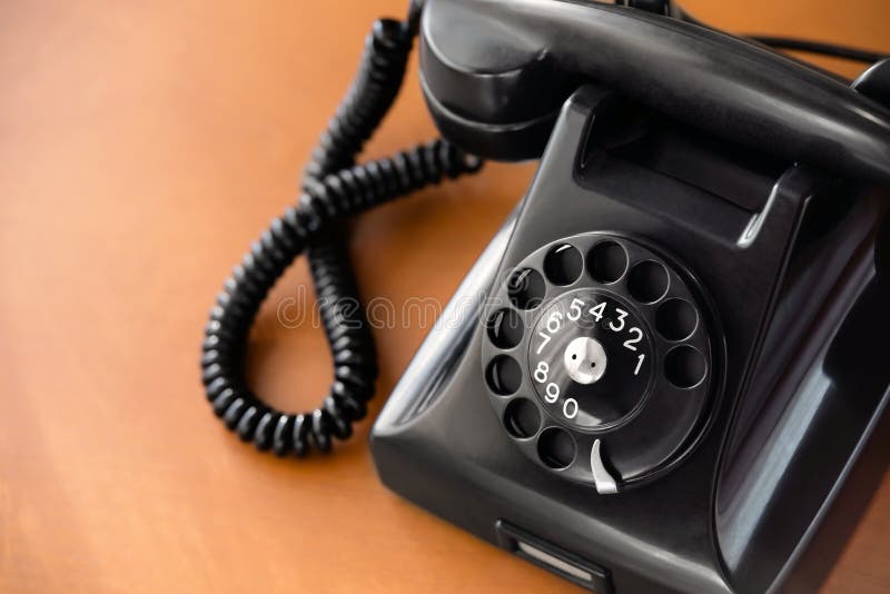 Old fashioned retro rotary dial phone on wooden desk, closeup. Old fashioned retro rotary dial phone on wooden desk, closeup