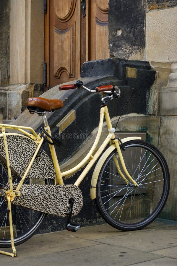 Altes gelbes Fahrrad Ledersitz mit Stoßdämpfern und Rad vor einer Kirche lizenzfreie stockbilder Altes gelbes Fahrrad Ledersitz mit Stoßdämpfern und Rad vor einer Kirche lizenzfreie stockbilder