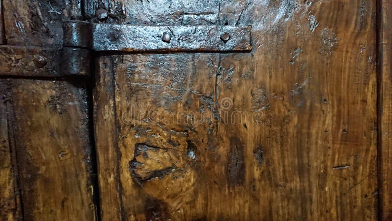 A hand crafted iron hinge set onto an oak wood door. A hand crafted iron hinge set onto an oak wood door.