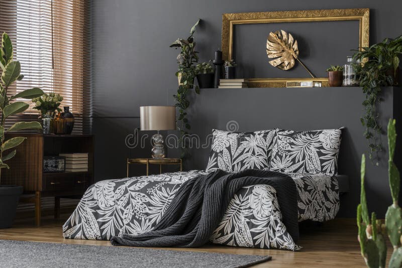 An old-fashioned wooden cabinet and an elegant golden leaf in frame art in a dark gray luxurious bedroom interior. An old-fashioned wooden cabinet and an elegant golden leaf in frame art in a dark gray luxurious bedroom interior