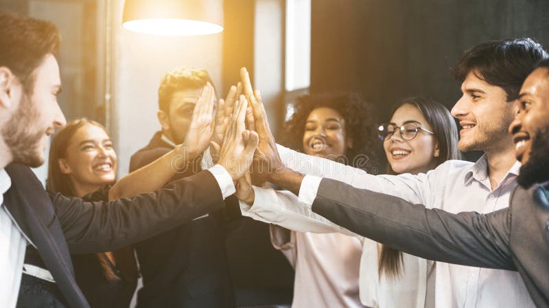 Alto-cinco para el éxito Grupo diverso de colegas del negocio en oficina