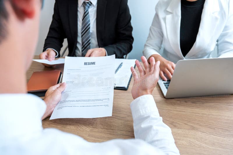 Alto diretivo hora que lê um resumo durante um candidato e um recrutamento da reunião do homem novo do empregado da entrevista de fotografia de stock Alto diretivo hora que lê um resumo durante um candidato e um recrutamento da reunião do homem novo do empregado da entrevista de fotografia de stock