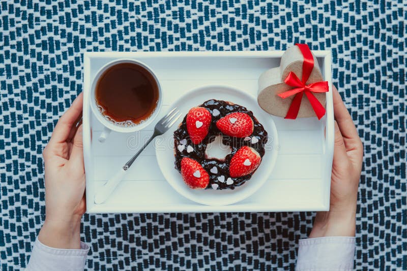 In alto le mani femminili che reggono un pasto romantico per l'amante. una tazza di tè con marmellata decorata con fragole e fotografie stock libere da diritti