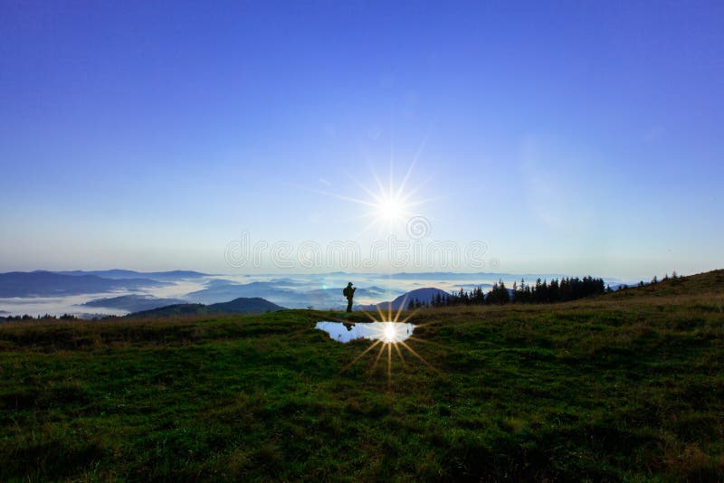 Alto nas montanhas acima das nuvens um homem novo está procurando uma conexão celular que guarda seu telefone altamente fotografia de stock Alto nas montanhas acima das nuvens um homem novo está procurando uma conexão celular que guarda seu telefone altamente fotografia de stock
