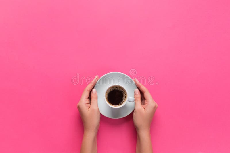 Alto ángulo de las manos de la mujer que sostienen la taza de café en el estilo rosado de Minimalistic del fondo La endecha plana fotos de archivo libres de regalías