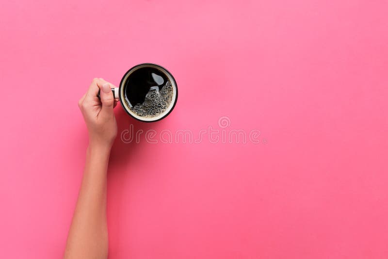 Alto ángulo de las manos de la mujer que sostienen la taza de café en el estilo rosado de Minimalistic del fondo La endecha plana imágenes de archivo libres de regalías