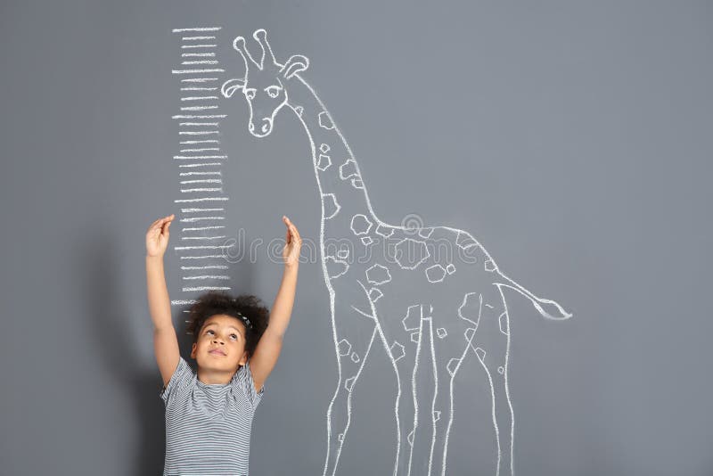 Altura de medición del niño afroamericano cerca del dibujo de la jirafa de la tiza en gris foto de archivo libre de regalías Altura de medición del niño afroamericano cerca del dibujo de la jirafa de la tiza en gris foto de archivo libre de regalías