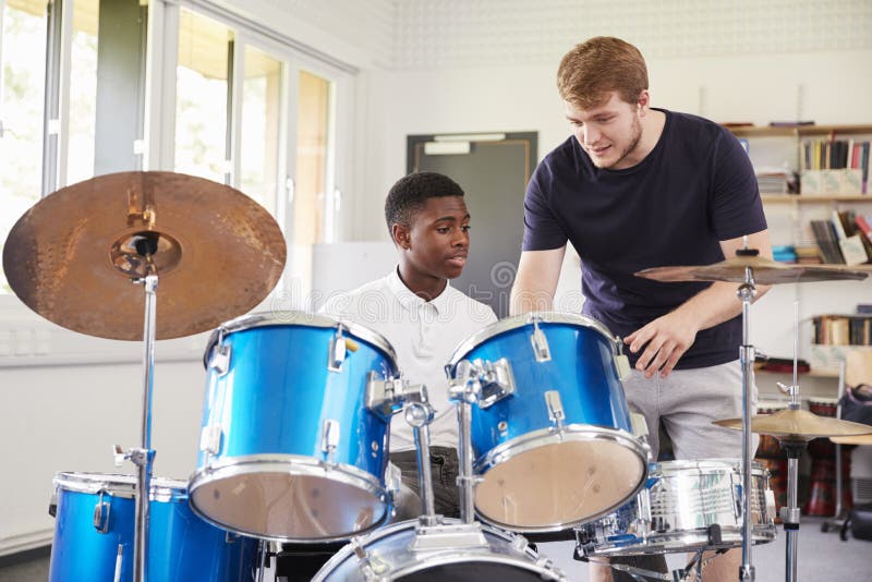 Aluno masculino com lição de música de Playing Drums In do professor fotos de stock royalty free Aluno masculino com lição de música de Playing Drums In do professor fotos de stock royalty free