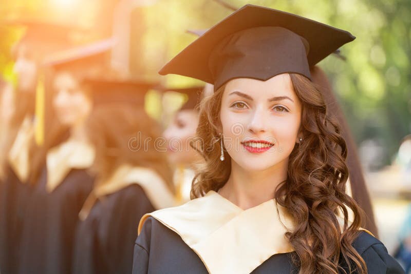 Graduate students wearing graduation hat and gown, outdoors. Graduate students wearing graduation hat and gown, outdoors