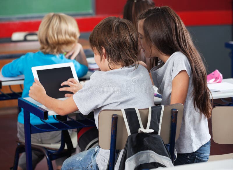 Alunos que usam a tabuleta de Digitas na sala de aula imagens de stock Alunos que usam a tabuleta de Digitas na sala de aula imagens de stock