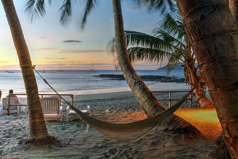 Amaca sulla spiaggia tropicale al tramonto immagini stock