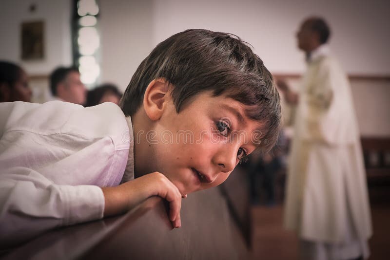AMADORA/PORTUGAL- 25 août 2015 - enfant dans l'église avec le prêtre derrière image libre de droits AMADORA/PORTUGAL- 25 août 2015 - enfant dans l'église avec le prêtre derrière image libre de droits