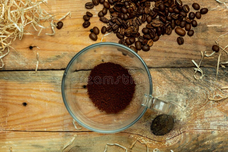 Amantes del café - una taza de cristal con café instantáneo al lado de los granos de café asados, en una tabla de madera, natural imagen de archivo Amantes del café - una taza de cristal con café instantáneo al lado de los granos de café asados, en una tabla de madera, natural imagen de archivo