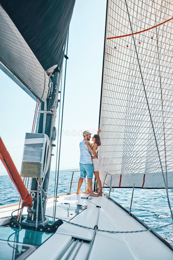 Amantes novos que passam o tempo feliz em um iate no mar imagem de stock Amantes novos que passam o tempo feliz em um iate no mar imagem de stock