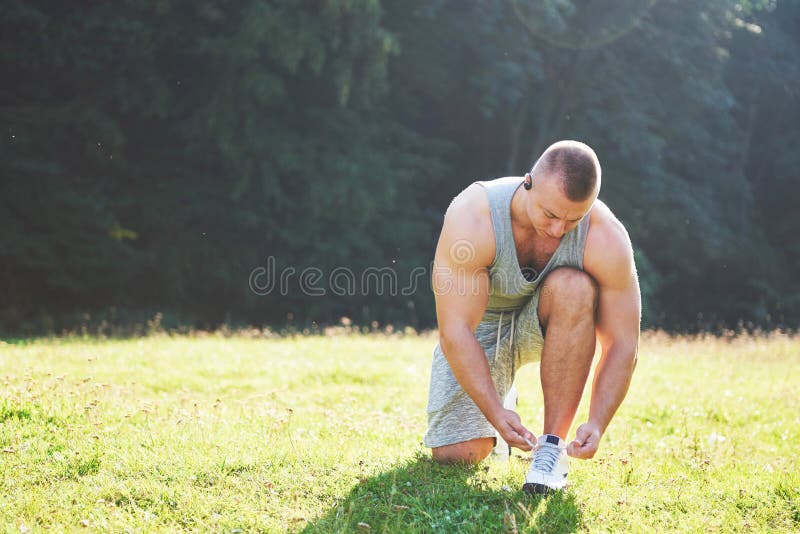 Amarrando a sapata dos esportes Um desportista novo que preparam-se para atlético e aptidão que treina fora Esporte, exercício, a imagem de stock royalty free Amarrando a sapata dos esportes Um desportista novo que preparam-se para atlético e aptidão que treina fora Esporte, exercício, a imagem de stock royalty free
