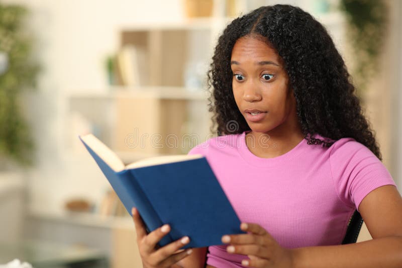 Amazed black woman reading a paper book stock photography