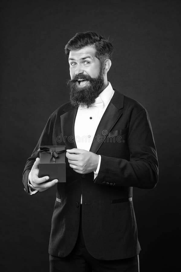 Amazed happy man in tuxedo bow tie formalwear on black background with box. shopping sale royalty free stock photography