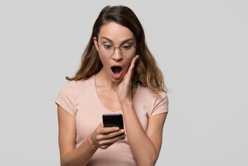Shocked surprised girl looking at phone isolated on blank background