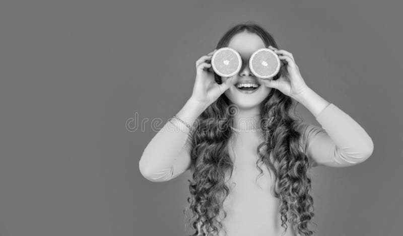 Amazed teen girl hold orange fruit on pink background with copy space royalty free stock photos