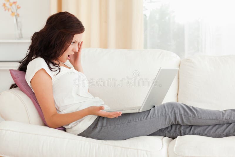 Amazed woman with a notebook on a sofa