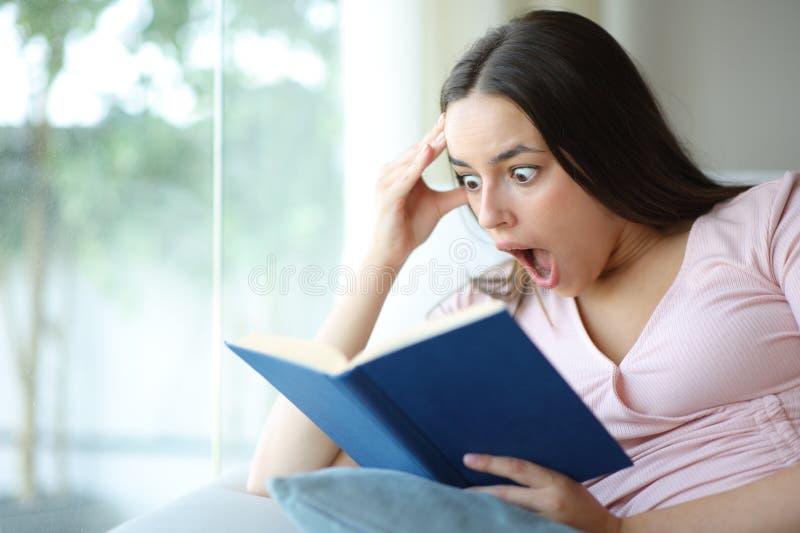Amazed woman reading a aper book at home royalty free stock image