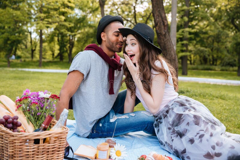 Amazed woman talking and having picnic with her boyfriend