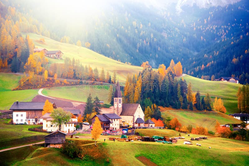 Amazing autumn scenery in Santa Maddalena village with church, colorful trees and meadows under rising sun rays. Dolomite Alps, South Tyrol, Italy. Amazing autumn scenery in Santa Maddalena village with church, colorful trees and meadows under rising sun rays. Dolomite Alps, South Tyrol, Italy.