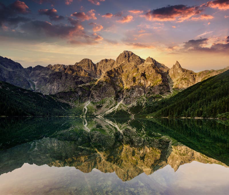 Amazing landscape of Tatra Mountains at sunset. View of high rocks, illuminated peaks and stones, reflected in mountain lake Mors